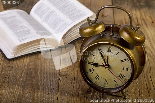 Image of Bible with clock on wood