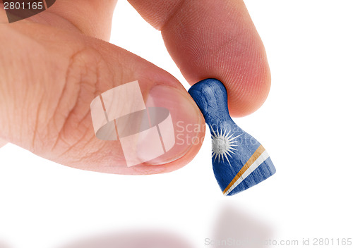 Image of Hand holding wooden pawn, flag painting, selective focus