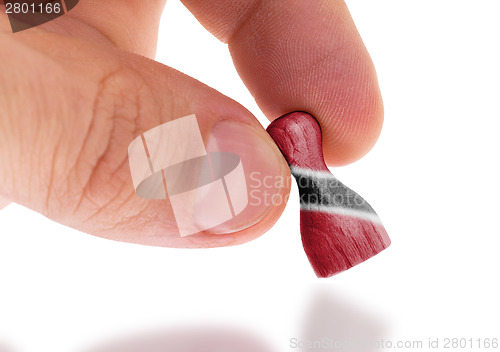 Image of Hand holding wooden pawn, flag painting, selective focus