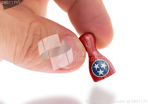 Image of Hand holding wooden pawn, flag painting, selective focus