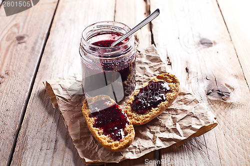 Image of black currant jam in glass jar and crackers