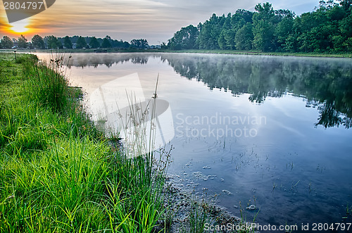 Image of sun rising over a foggy lake early morning