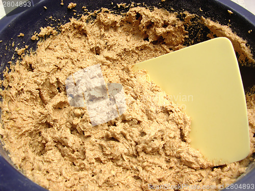 Image of Mixed unbaken chocolate dough in a bowl with dough scraper