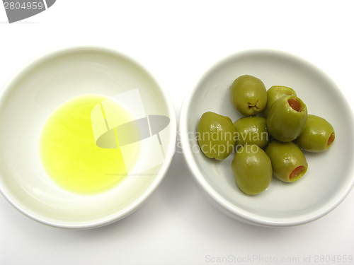 Image of Two bowls of chinaware with olive oil and olives on white background