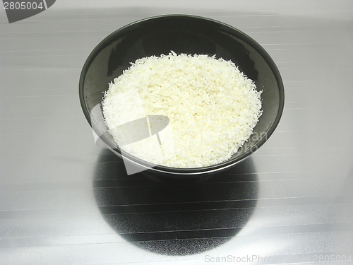 Image of Black bowl of chinaware with coconut flakes on reflecting surface