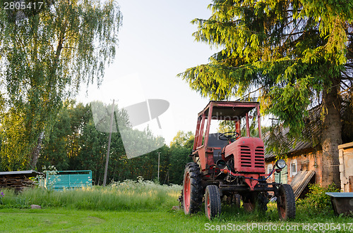 Image of village farm red old tractor in meadow summer time 