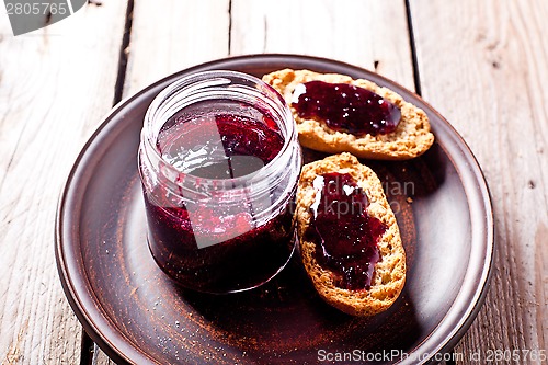 Image of black currant jam in glass jar and crackers 