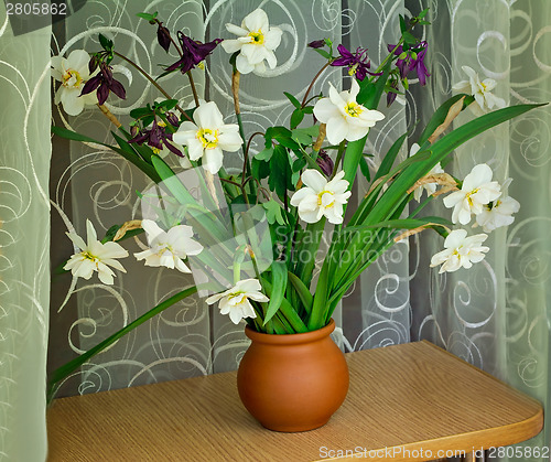 Image of Blossoming narcissuses in a vase on a table.