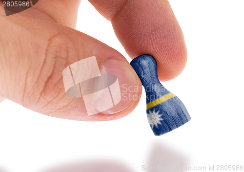 Image of Hand holding wooden pawn, flag painting, selective focus