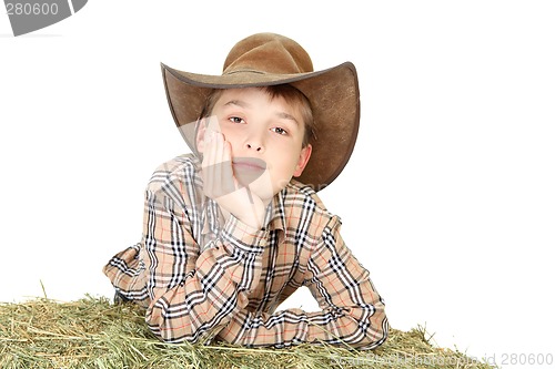 Image of Farm boy leaning on lucerne bale