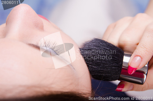 Image of Makeup artist powders face of a beautiful girl