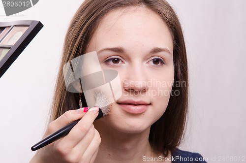 Image of Makeup. Makeup artist applies powder on cheeks