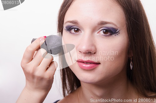 Image of Makeup artist brush powder on face causes model