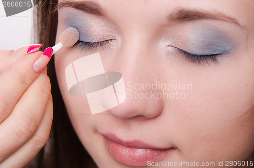 Image of Makeup artist is shaded eyelids model with makeup