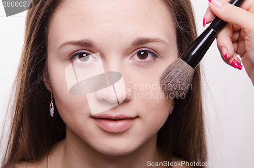 Image of Makeup artist applies powder on cheeks model