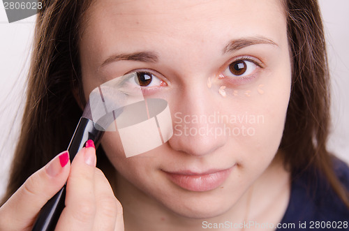 Image of Makeup artist brush smears concealer on the eyelids model