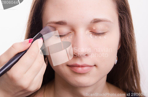 Image of Makeup artist is shaded brush concealer on eyelids model