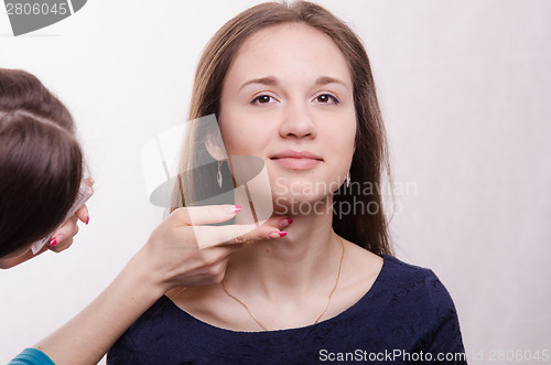 Image of Beautiful model makeup artist applied concealer on neck