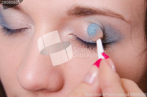 Image of Makeup artist is shaded eyelids as makeup