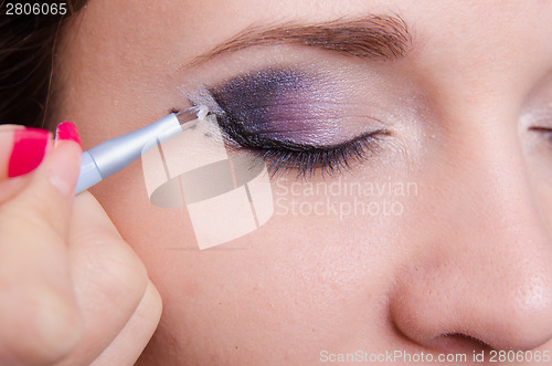 Image of Makeup artist draws arrows on the right eye girl