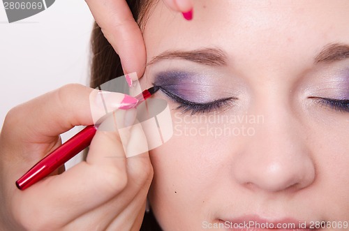 Image of Bright makeup. Makeup artist begins to draw arrows