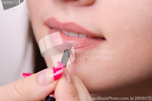 Image of Makeup artist paints a lip pencil model