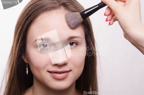 Image of Makeup artist applies powder on face of a beautiful girl