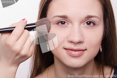 Image of Makeup artist applies powder on cheeks of a pretty girl