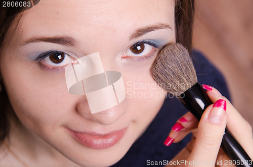 Image of Makeup artist applies powder on face of beautiful girl