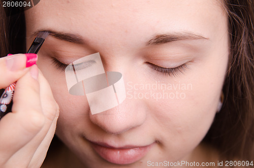 Image of Makeup artist brush eyebrows brings young girl
