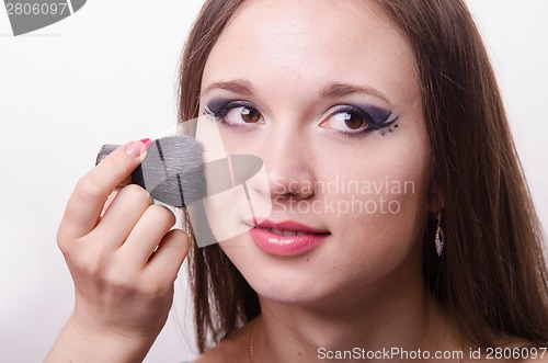 Image of Makeup artist applies powder on face of beautiful model