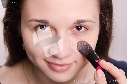 Image of Makeup artist is shaded concealer brush on face model