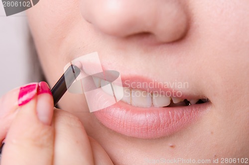 Image of Makeup artist paints a lip pencil woman