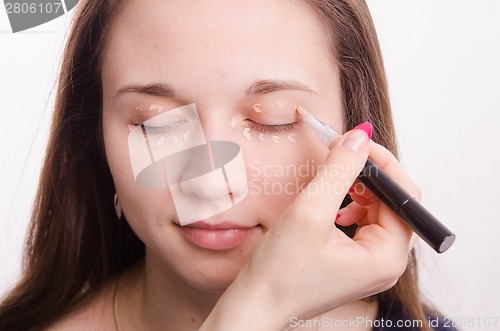 Image of Makeup artist applies foundation on eyelids