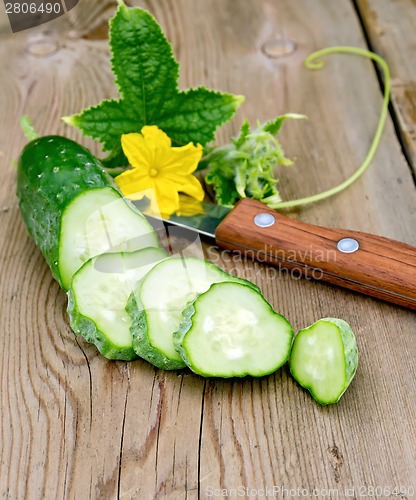 Image of Cucumber sliced with flower and knife on board