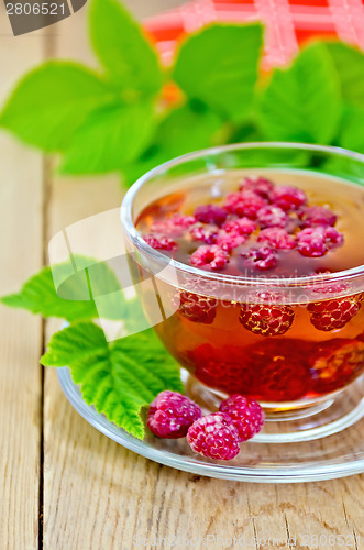 Image of Tea with raspberries in glass cup and napkin on board