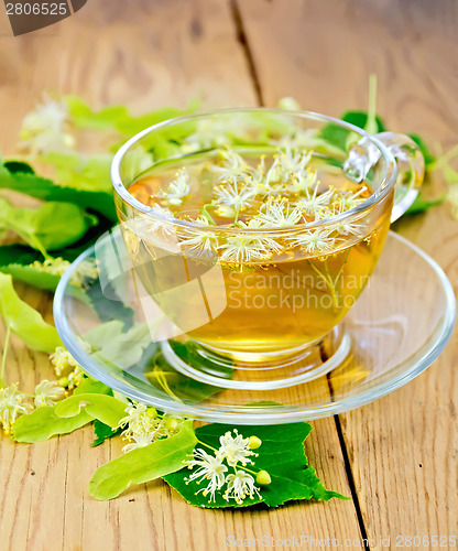 Image of Herbal tea from linden flowers in glass cup on board