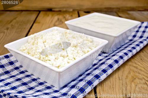 Image of Curd and sour cream in bowls on board with napkin