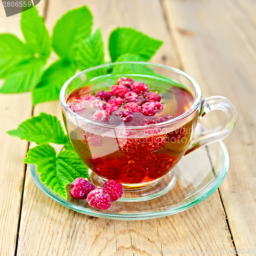 Image of Tea with raspberries in glass cup on board