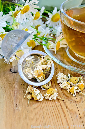 Image of Herbal chamomile tea with strainer on board