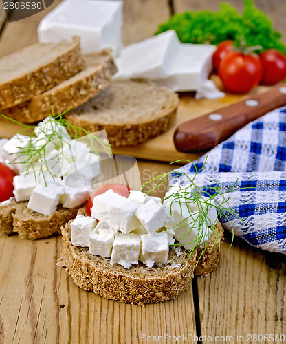 Image of Bread with feta and tomatoes on board with knife