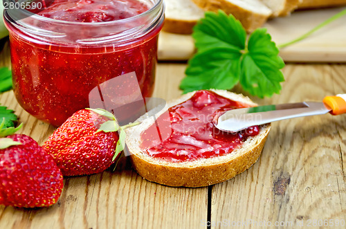 Image of Bread with strawberry jam and a knife on board