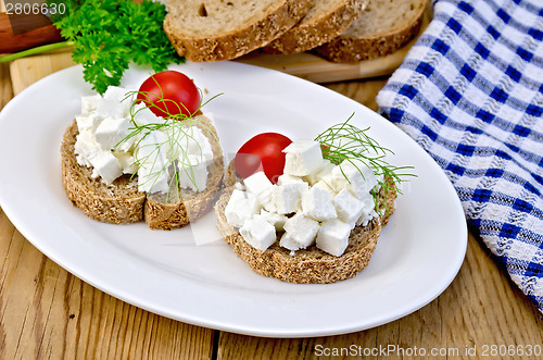 Image of Bread with feta and tomatoes on plate on board