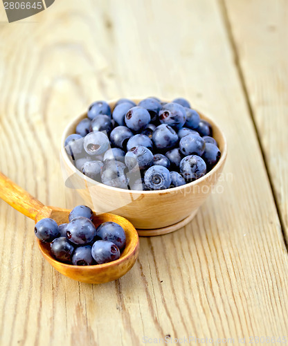 Image of Blueberries in wooden bowl and spoon on board