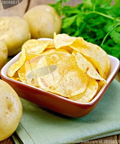 Image of Chips in bowl with potato on napkin and board