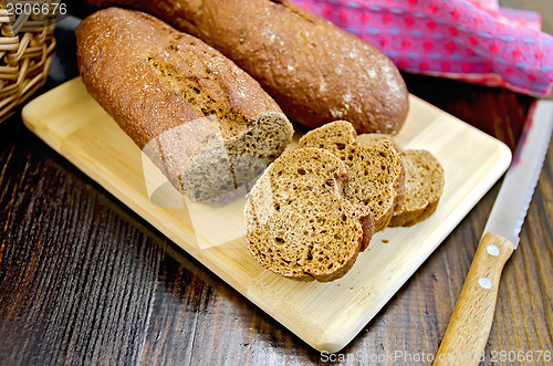 Image of Rye baguettes with a knife and basket on board