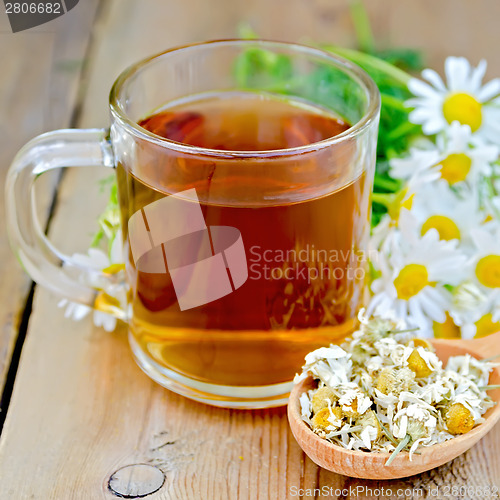 Image of Herbal chamomile tea in glass mug on board