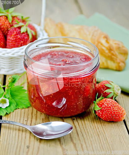 Image of Jam of strawberry with bun and spoon on board