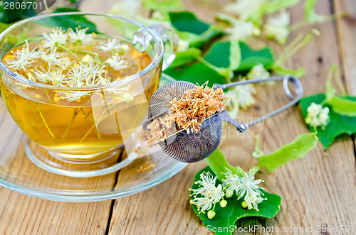 Image of Herbal tea from linden flowers with strainer on board