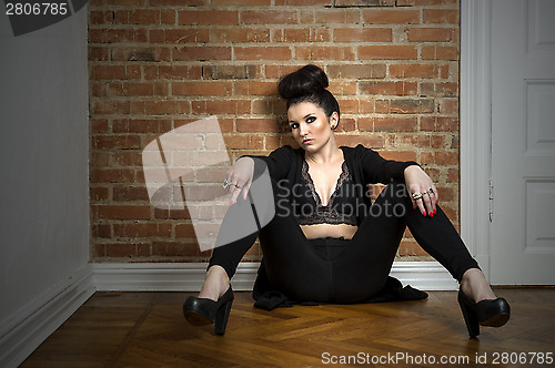 Image of Moody elegant woman sitting on a parquet floor